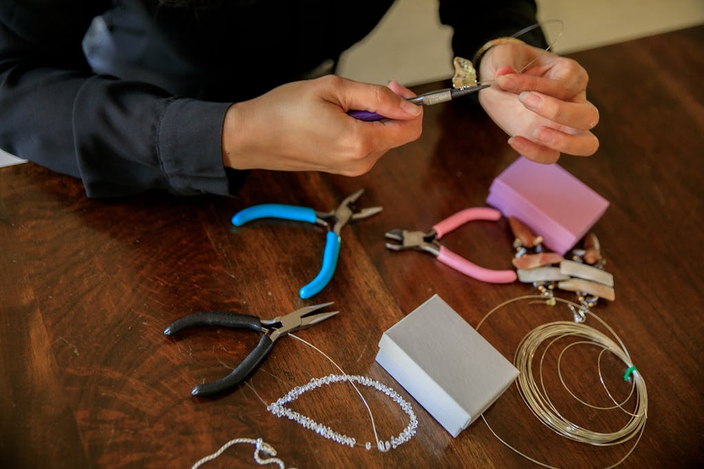 A close-up of hands crafting a necklace using pliers and tools, perfect for DIY jewelry enthusiasts.